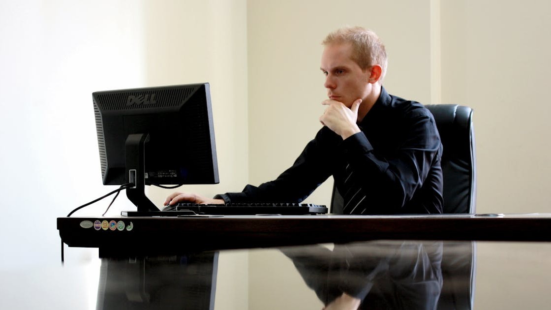 Analyst-level professional reviewing information on a computer in a quiet office setting.